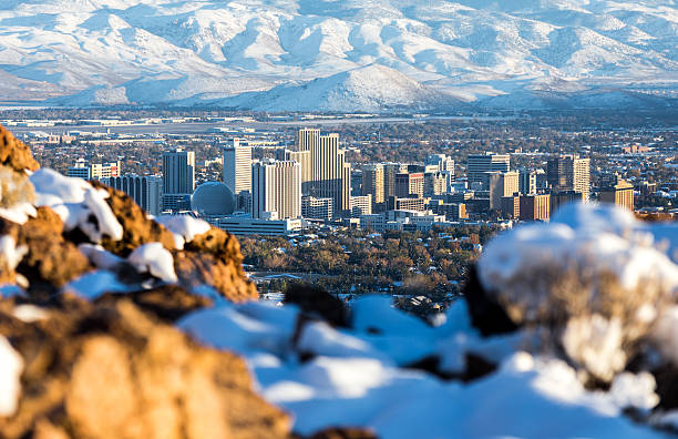 Image of a city with some tall building surrounded by hills covered in snow.